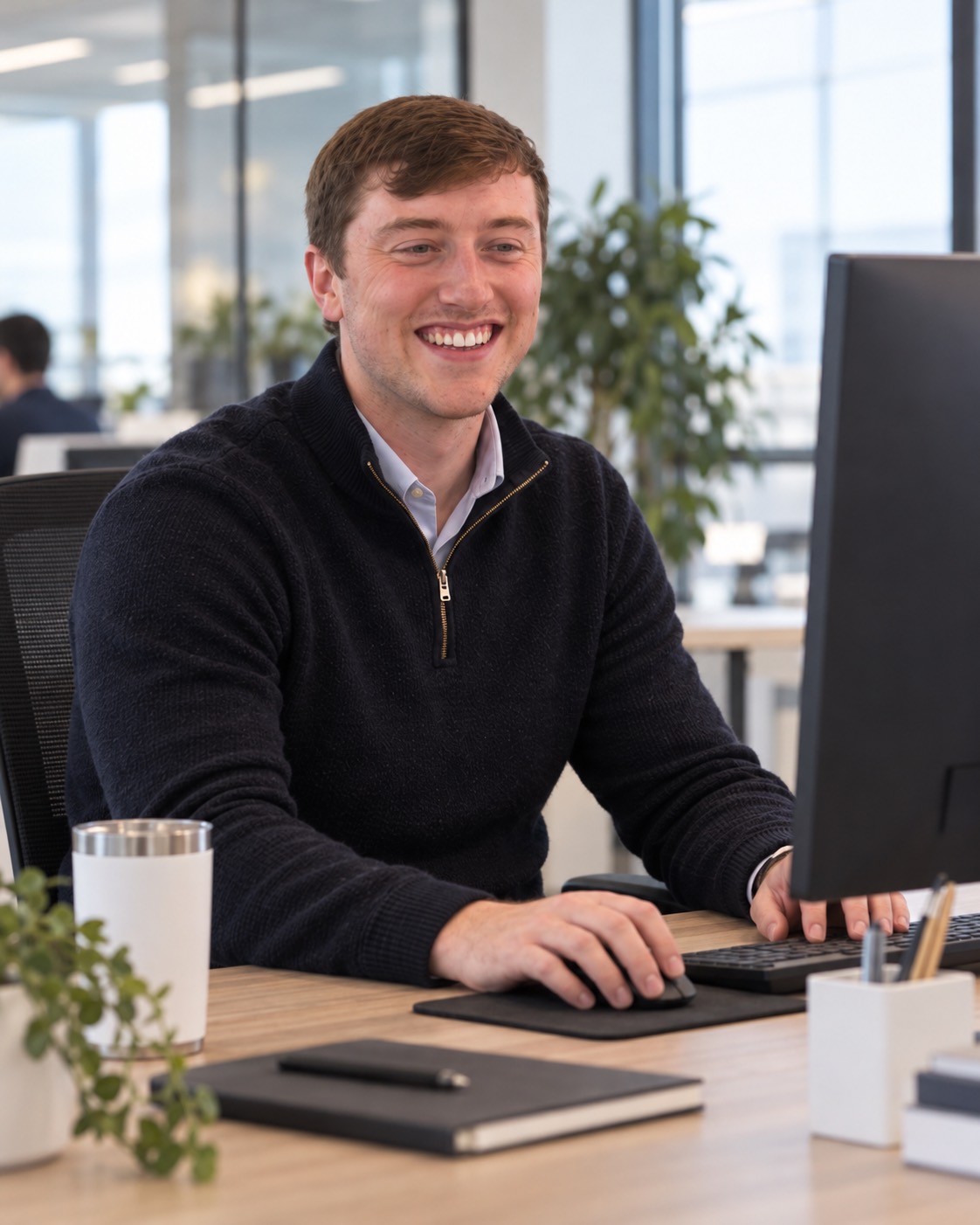 A Cloud & More engineer smiling at a desk in the office